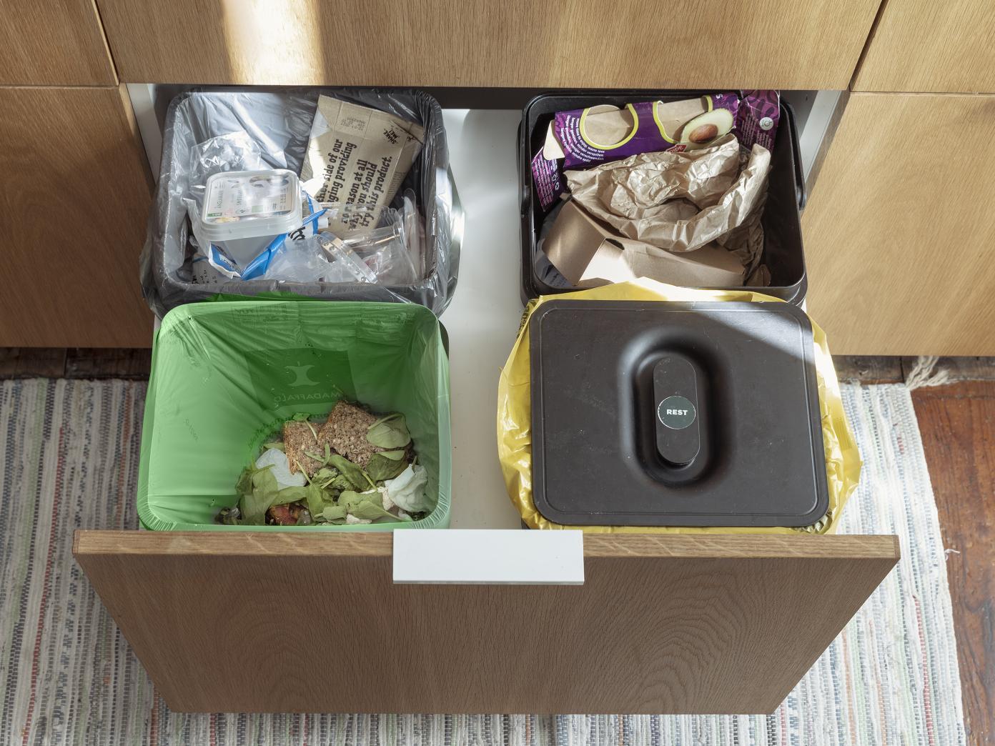 Skab med dyb skuffe under køkkenvasken. I skuffen står 4 affaldspande til plast, pap, rest og madaffald.